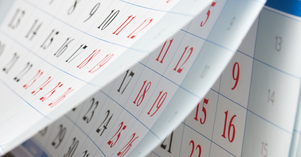 A side view shows a paper calendar with several pages lifted. Red and black numbers are on the calendar grids.